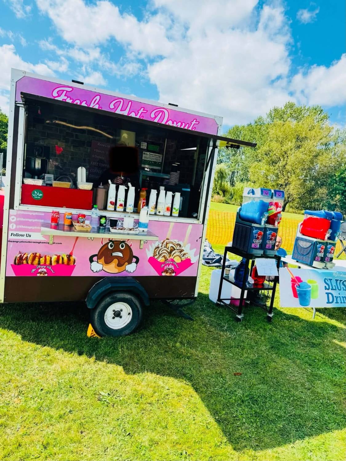 The Angry Donut trailer open for service on a sunny day, with slush machines beside it